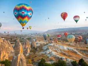 Dozens of colorful hot air balloons flying over the unique fairy chimneys and rock formations in Cappadocia.