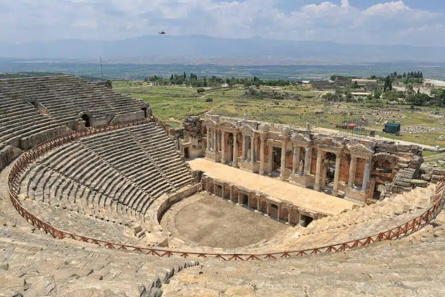 Ruins of ancient Pamukkale Theatre in Turkey, showcasing well-preserved stone seats and stage.