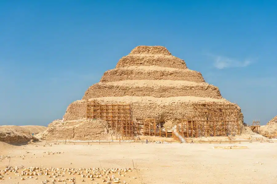 View of Saqqara Necropolis in Egypt, showcasing ancient pyramid structures, tombs, and desert landscape under a clear sky.