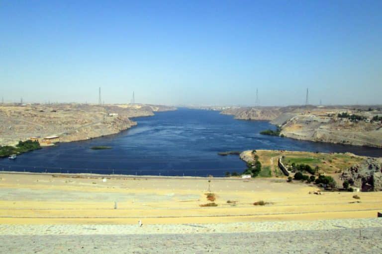 Panoramic view of the Aswan High Dam, showcasing its massive concrete structure spanning the Nile River under a clear blue sky.