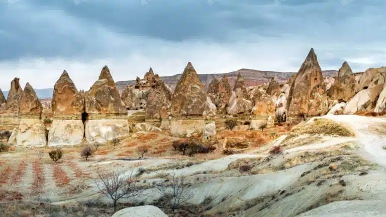 Cone-shaped rock formations in Cappadocia, Turkey, featuring eroded volcanic stone and scenic dry terrain.