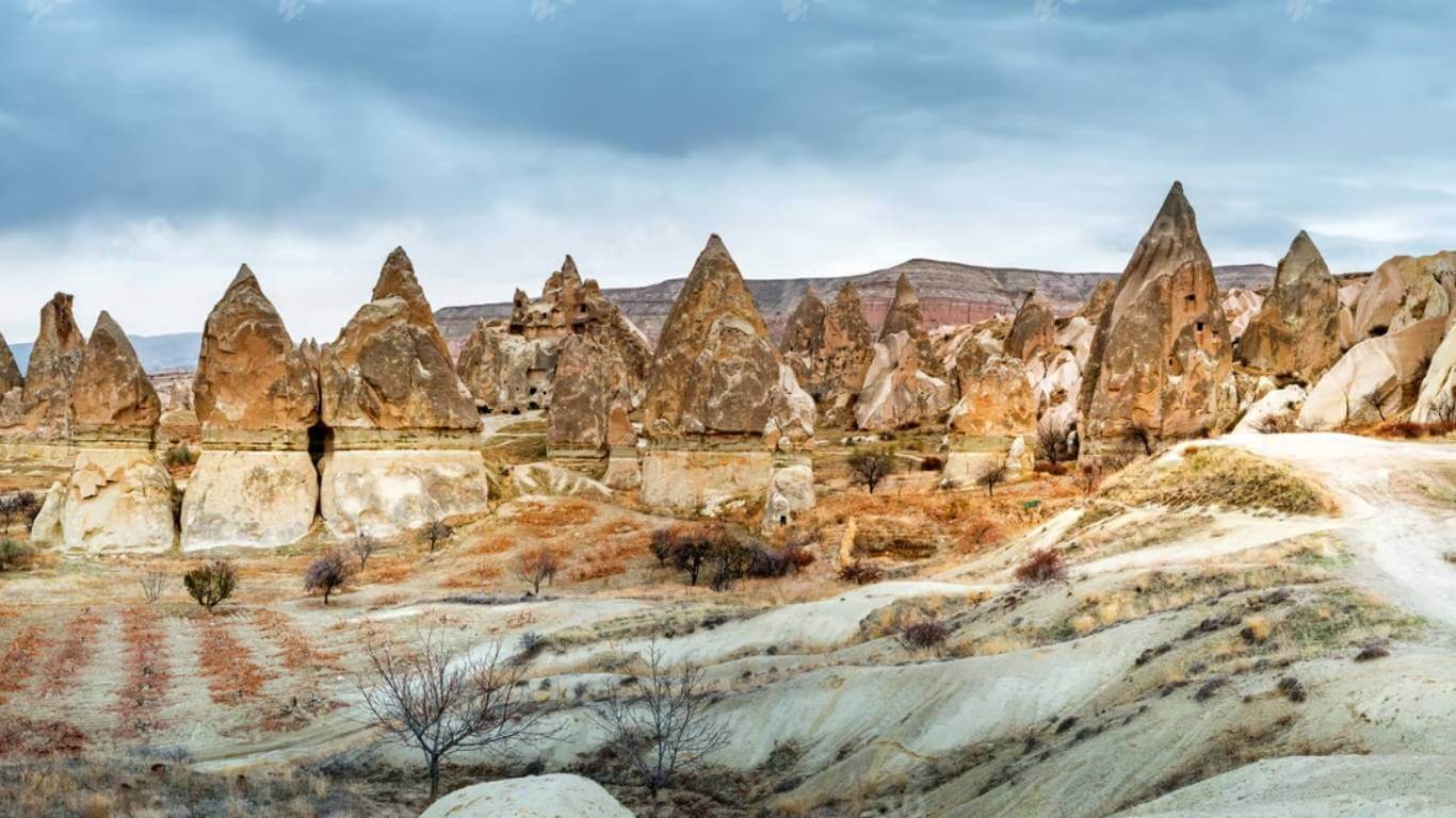 Cone-shaped rock formations in Cappadocia, Turkey, featuring eroded volcanic stone and scenic dry terrain.